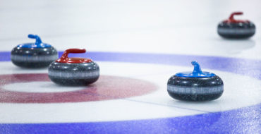 4 curling pucks on circle targets in the ice