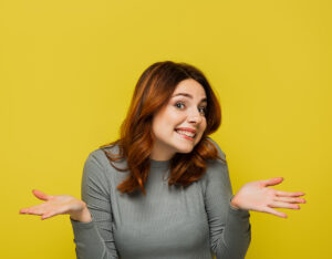 a red-headed white woman is shrugging with a "what are you gonna do?" grin on her face