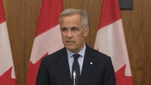 Mark Carney giving a speech in front of Canadian flags