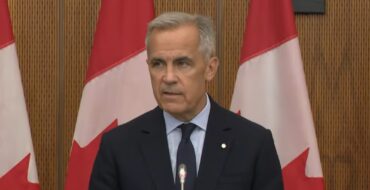 Mark Carney giving a speech in front of Canadian flags